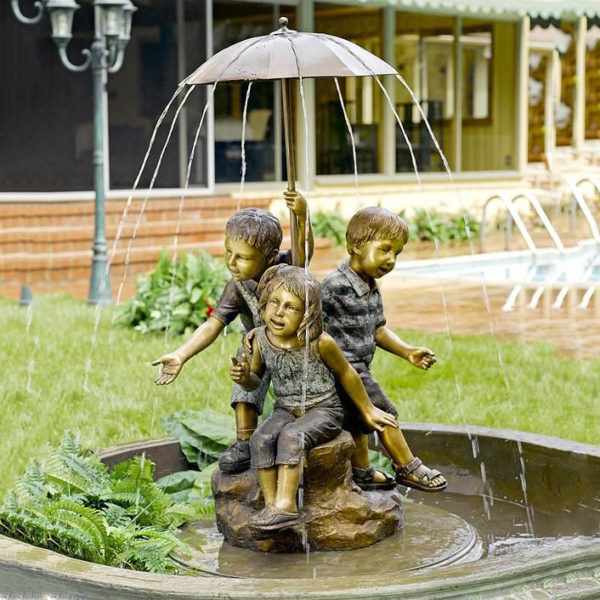Children carry bronze fountain sculptures with umbrellas